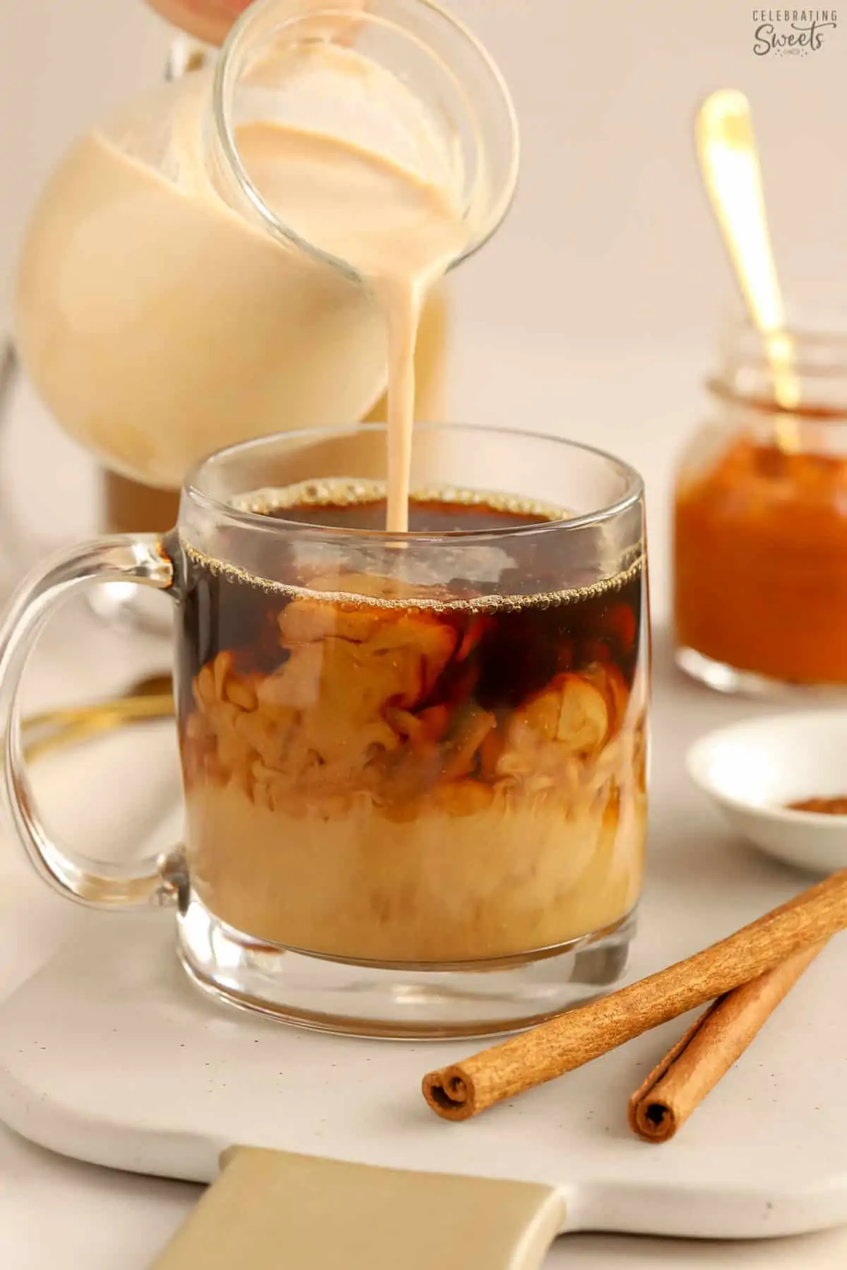 Pumpkin spice creamer being poured into a mug of black coffee.