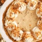 Butterfinger pie in a white pie plate topped with swirls of whipped cream.