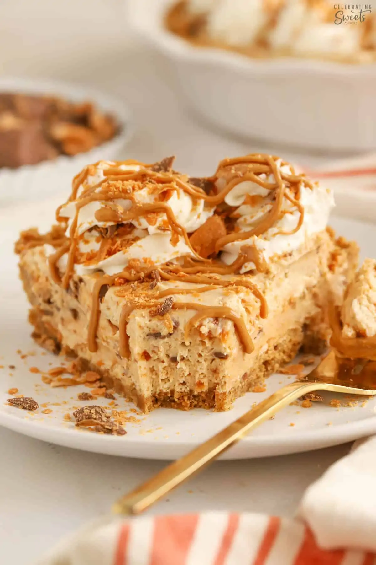 Slice of Butterfinger pie on a white plate garnished with whipped cream, peanut butter, and crushed Butterfinger.
