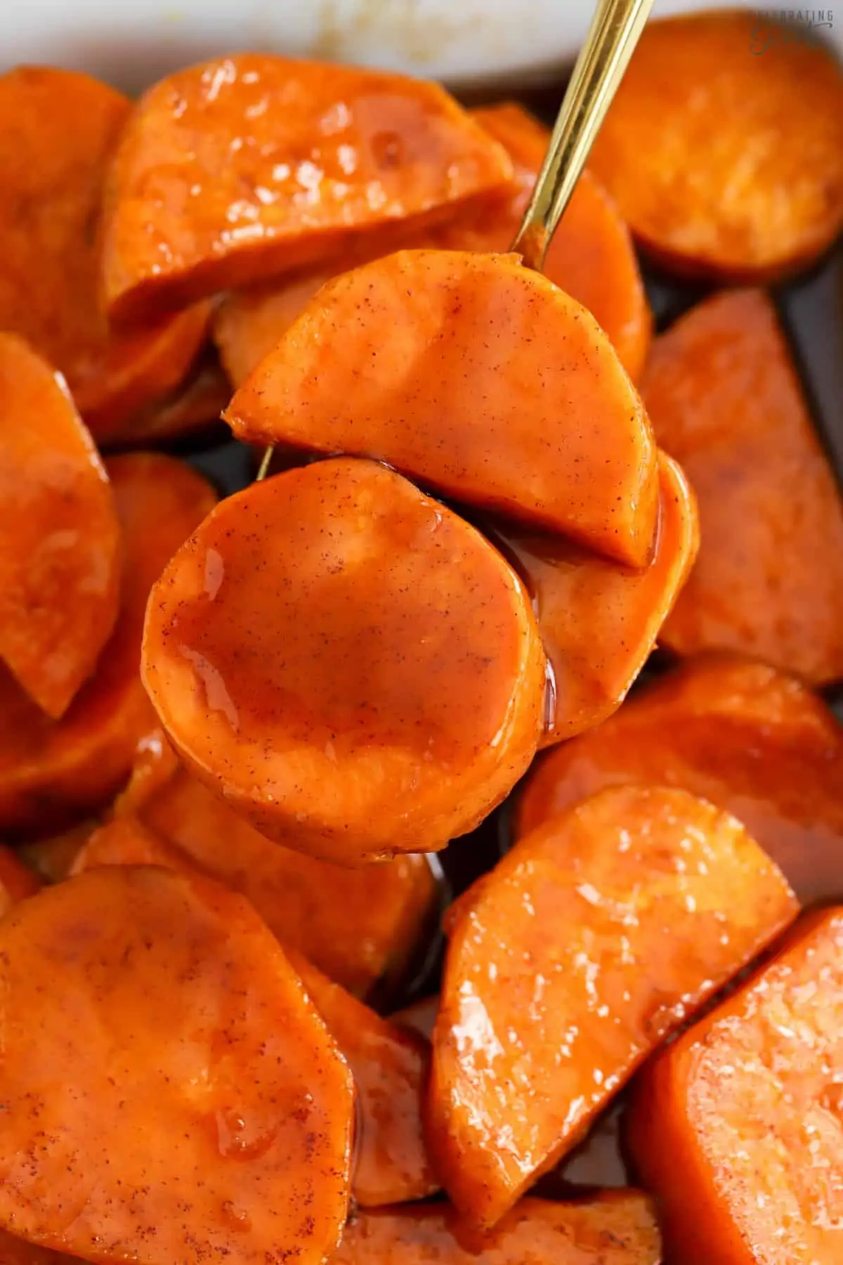 Closeup of candied sweet potatoes on a gold spoon.