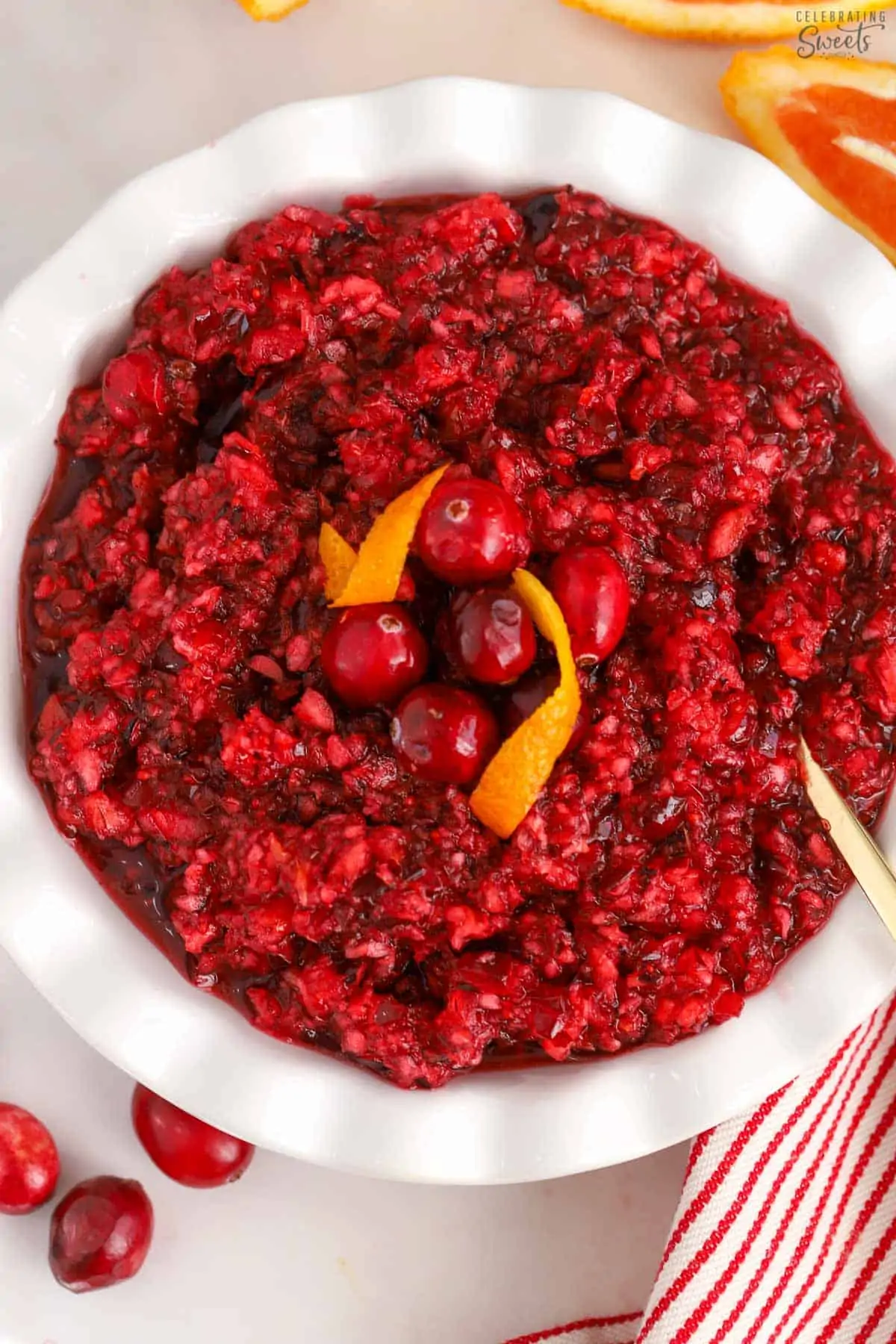 Closeup of cranberry orange relish in a white bowl with a gold spoon.