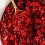 Closeup of cranberry orange relish in a white bowl with a gold spoon.