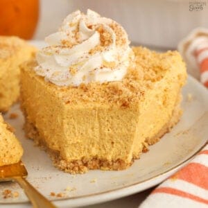 Slice of pumpkin pie cheesecake on a grey plate with a gold fork.