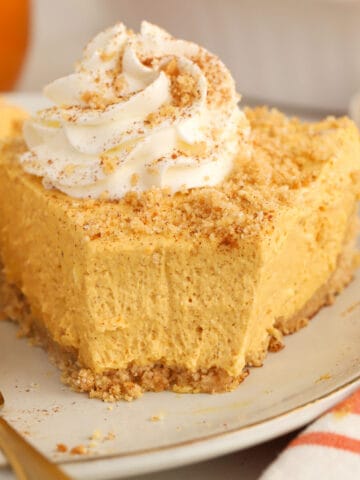 Slice of pumpkin pie cheesecake on a grey plate with a gold fork.
