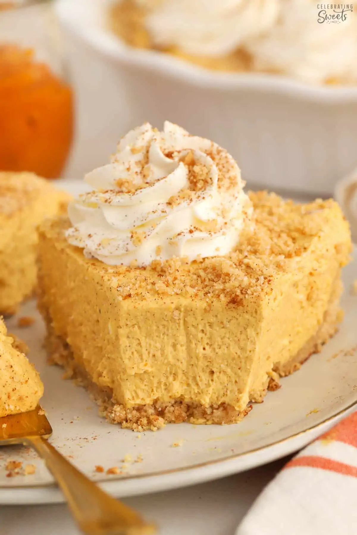 Slice of pumpkin pie cheesecake on a grey plate with a gold fork.