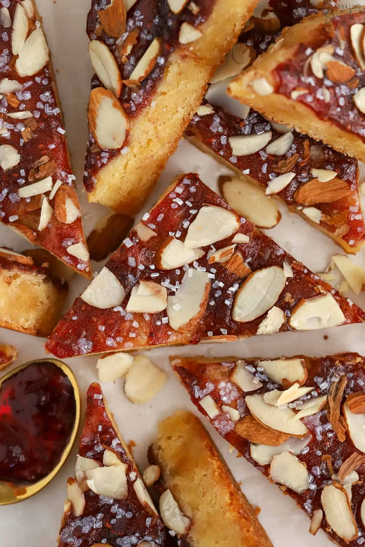 Almond bars cut into triangles on parchment paper.