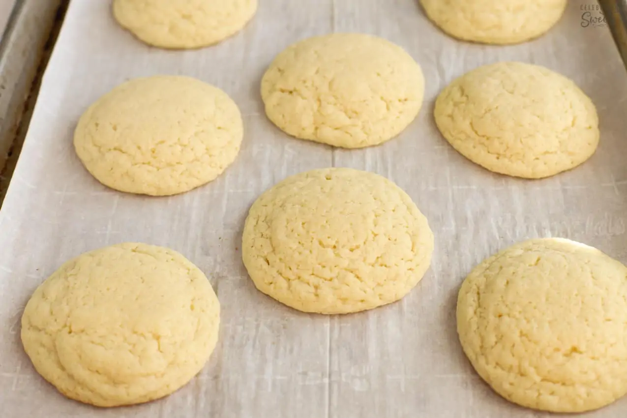 Sugar cookies on a parchment lined baking sheet.