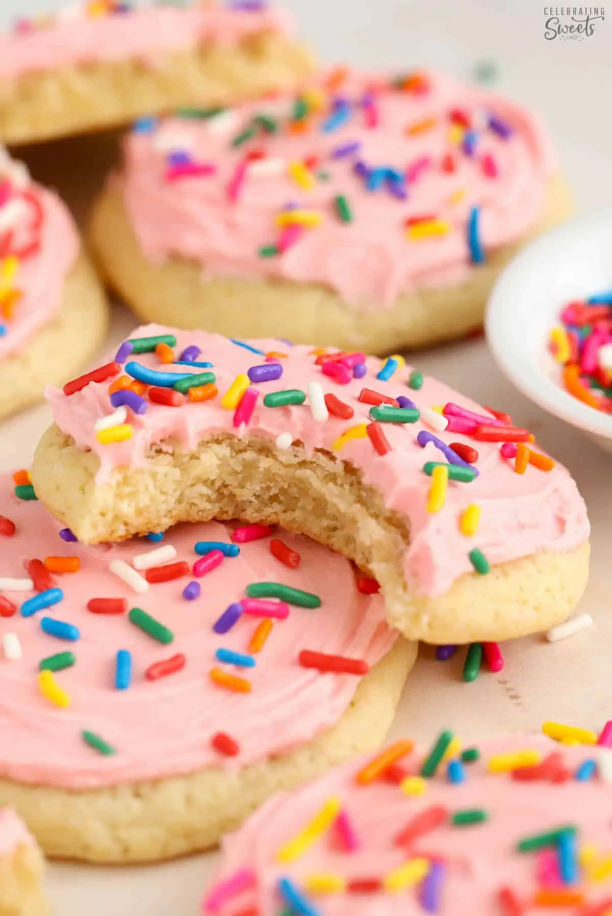 Frosted sugar cookies with pink frosting and colored sprinkles.