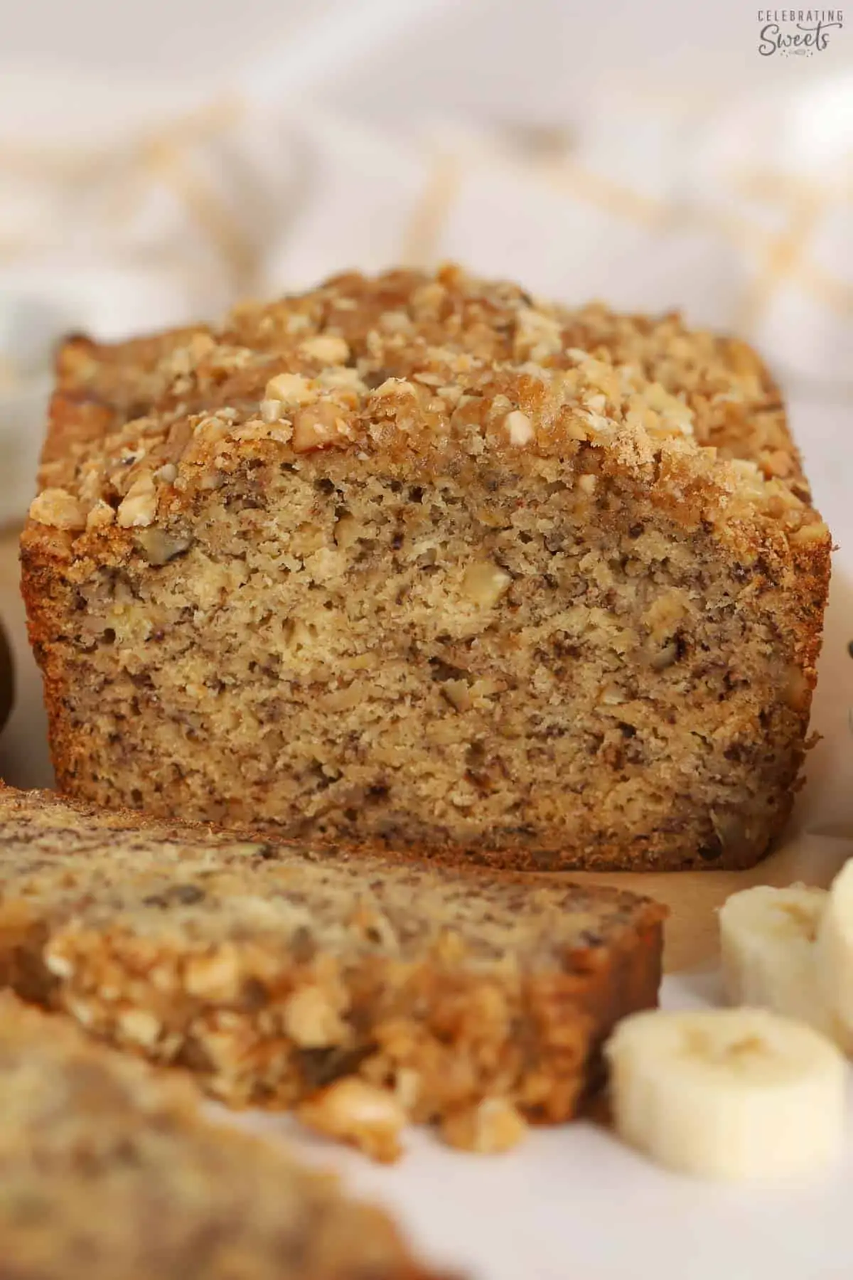 Loaf of banana nut bread cut open on a piece of parchment paper.