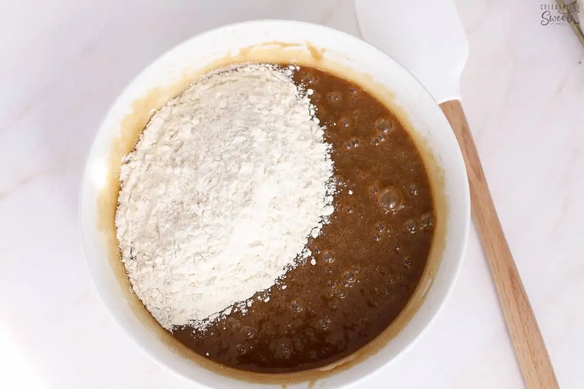 Blondie batter in a white bowl next to a rubber spatula.