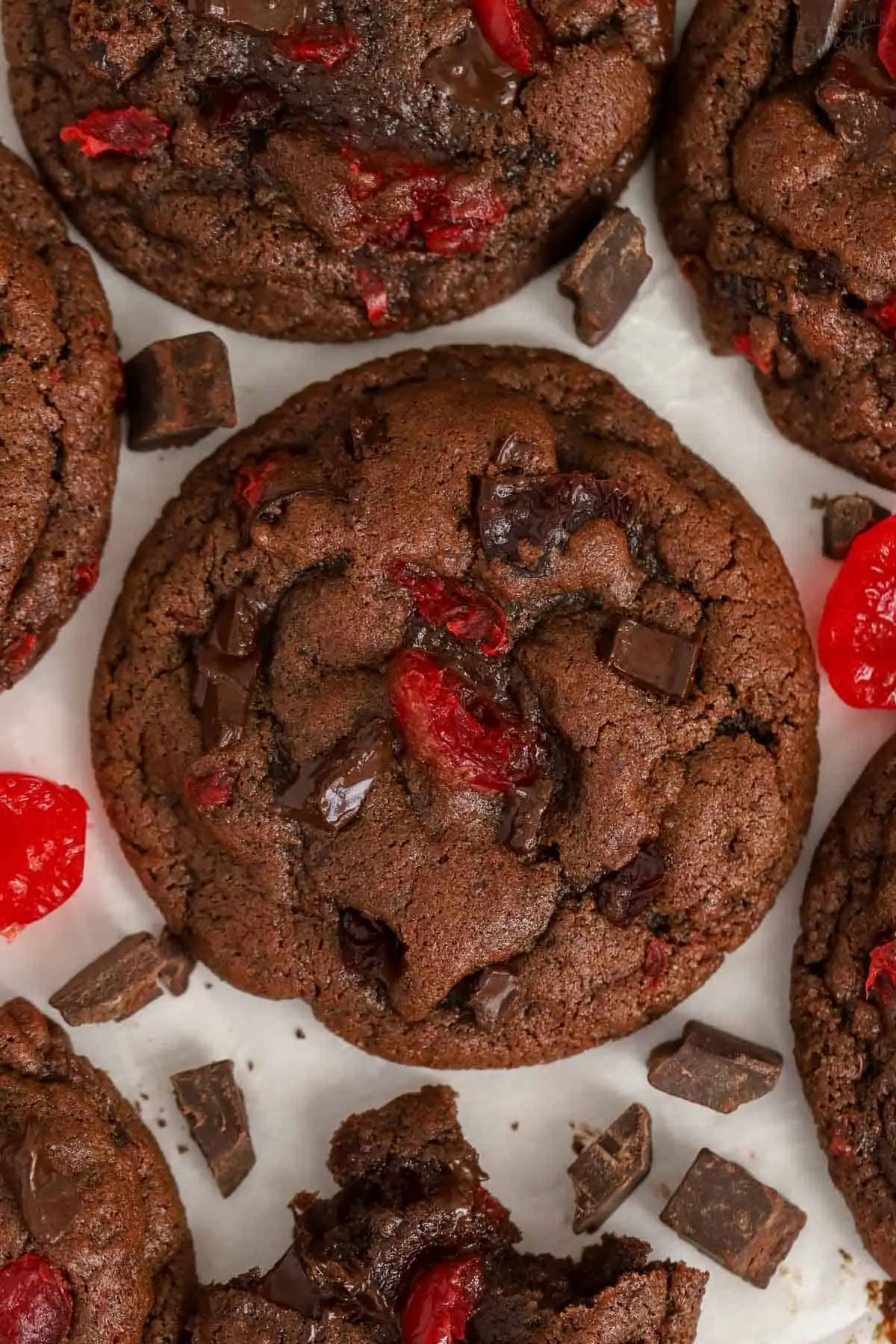 Closeup of chocolate cherry cookies on parchment paper.