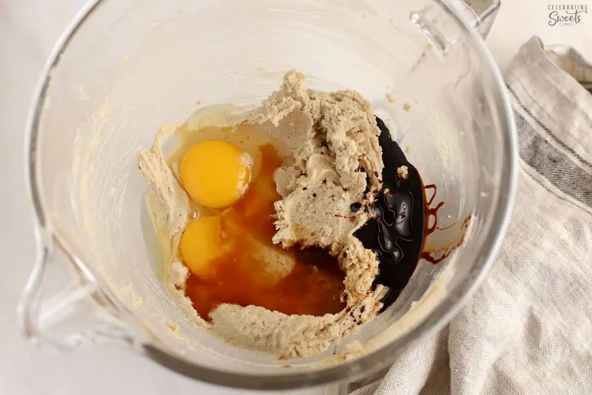 Cookie dough (eggs, butter, sugar, molasses) in a large glass bowl.