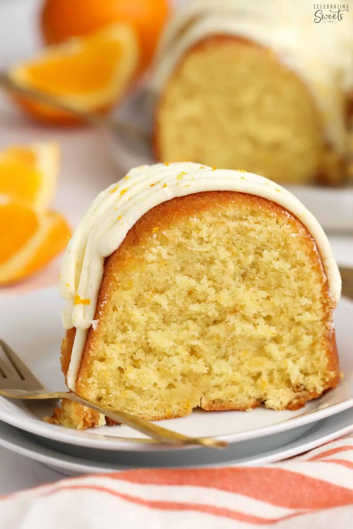 Slice of orange bundt cake on a white plate with a gold fork.
