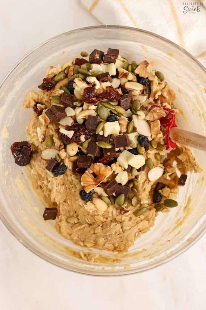 Trail mix cookie dough in a glass bowl with a red spatula.