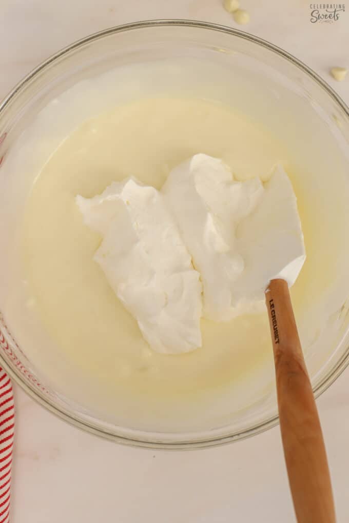 White chocolate mousse in a glass bowl with a rubber spatula.