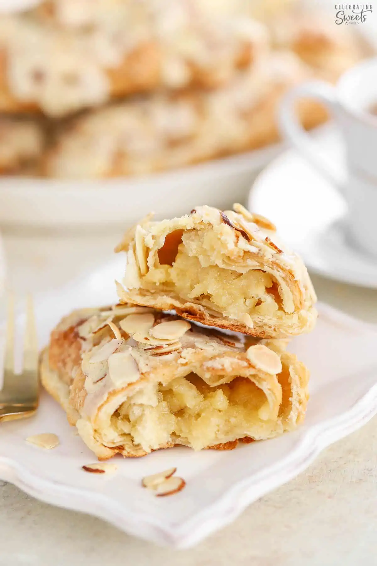 Almond croissants split in half on a white plate.