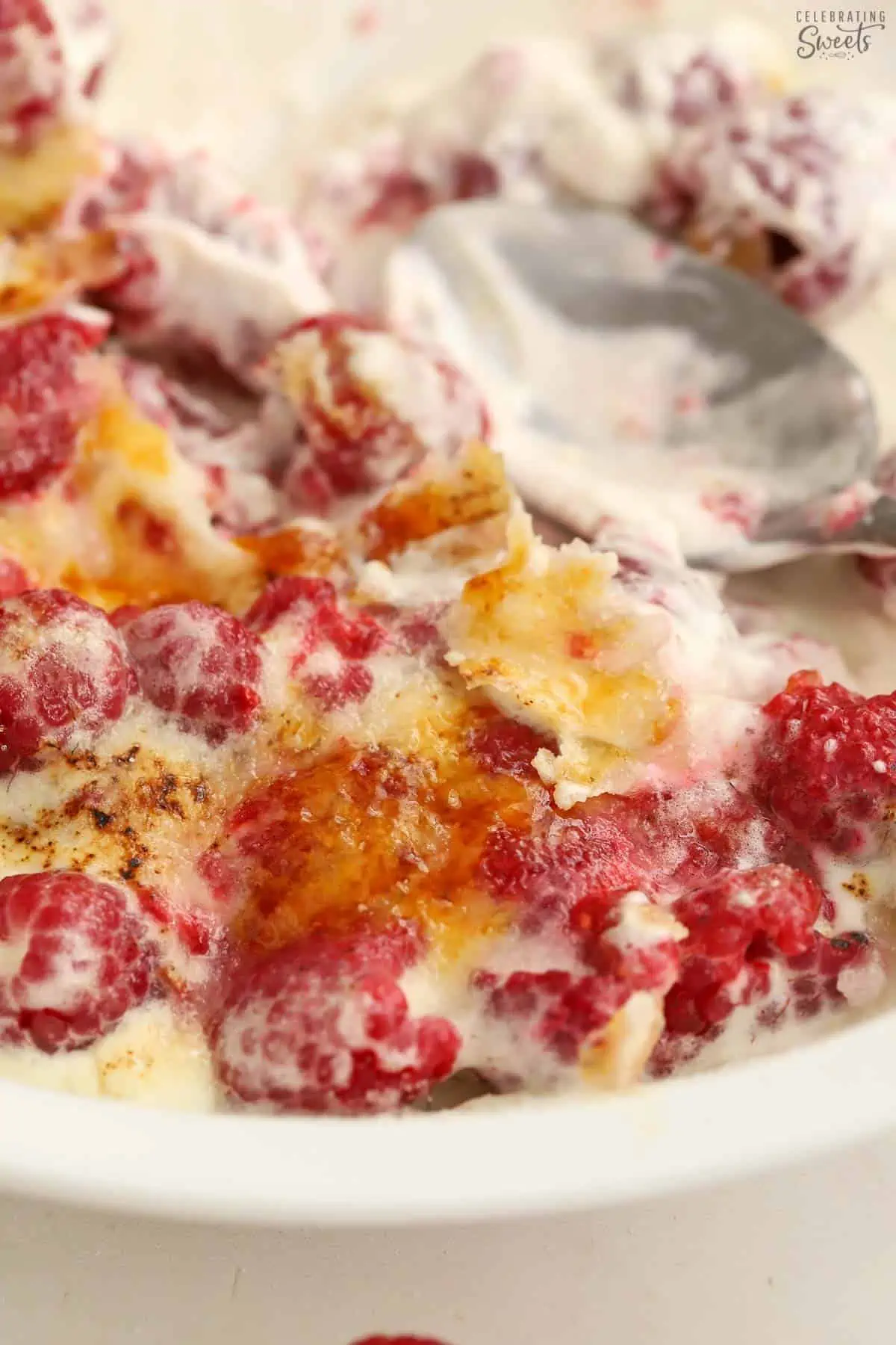 Berries, whipped cream, and caramelized sugar in a white baking dish.