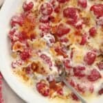 Berries, whipped cream, and caramelized sugar in a white baking dish.