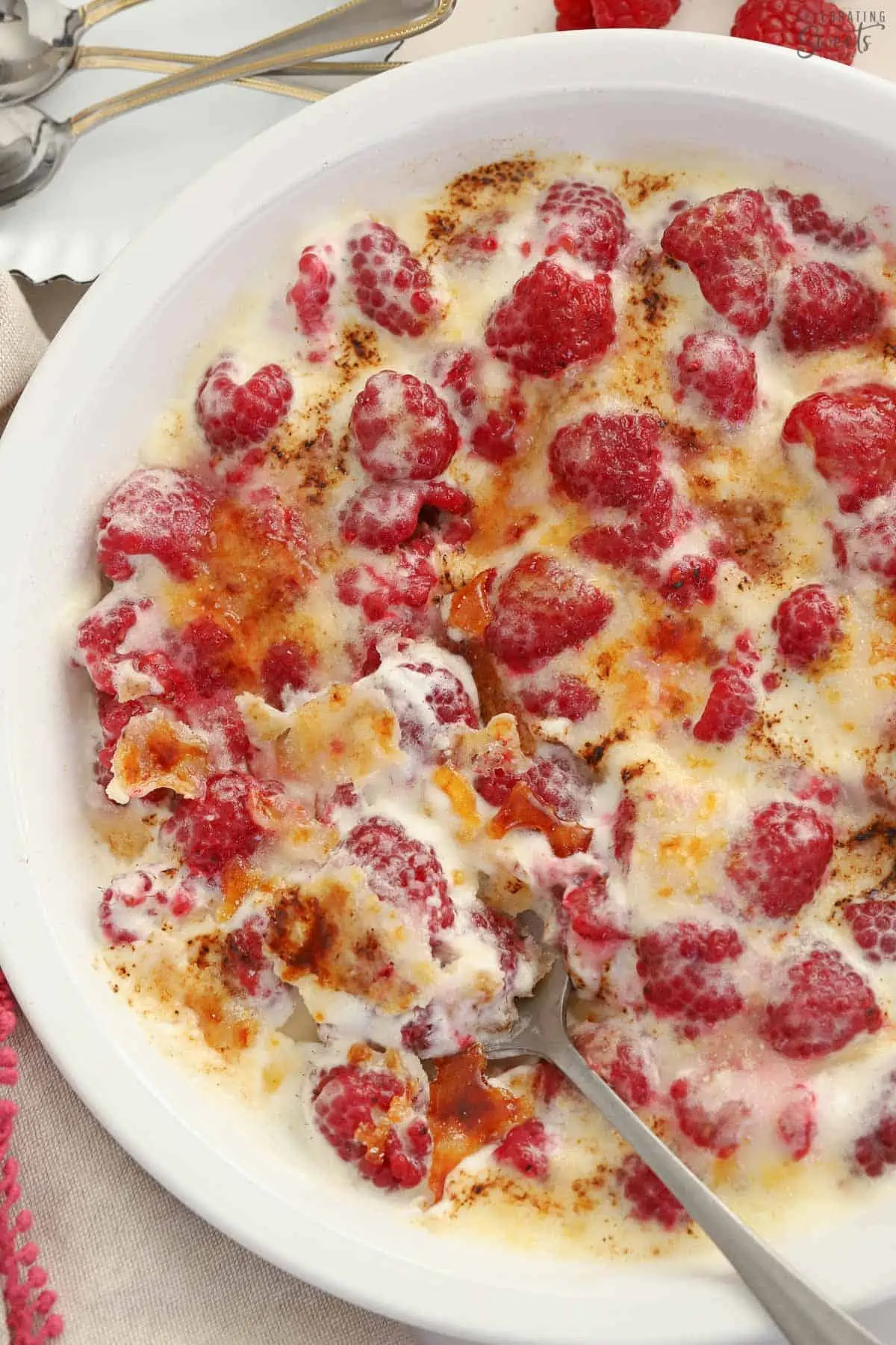 Berries, whipped cream, and caramelized sugar in a white baking dish.