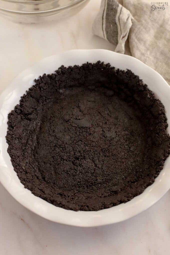 Oreo crust in a white pie dish.