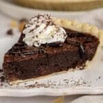 Slice of brownie pie topped with whipped cream and chocolate sauce.