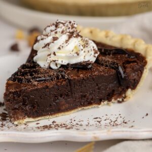 Slice of brownie pie topped with whipped cream and chocolate sauce.