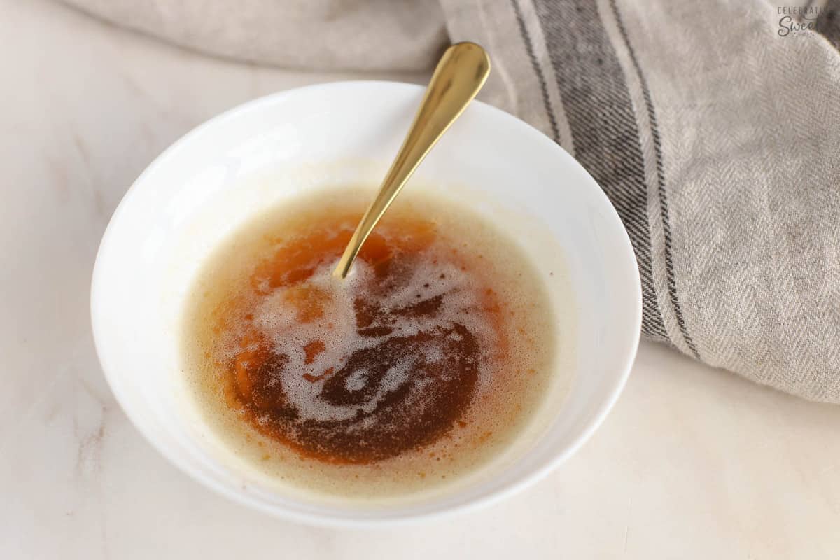 Brown butter in a whit bowl with a gold spoon.