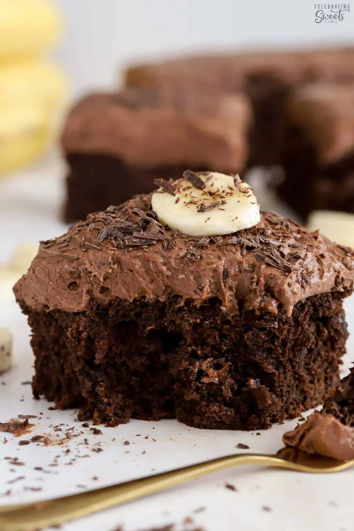 Slice of chocolate banana cake topped with chocolate frosting and sliced banana.
