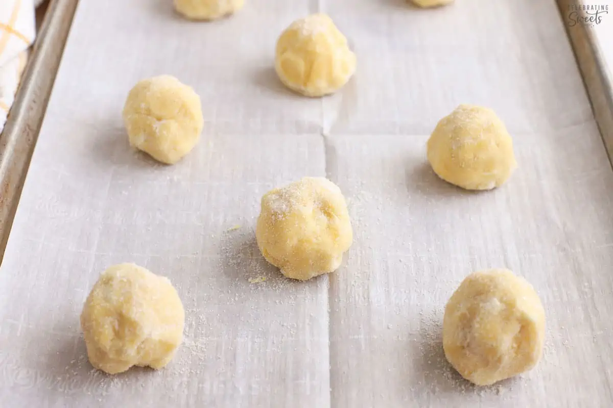 Cookie dough balls on a parchment lined baking sheet.