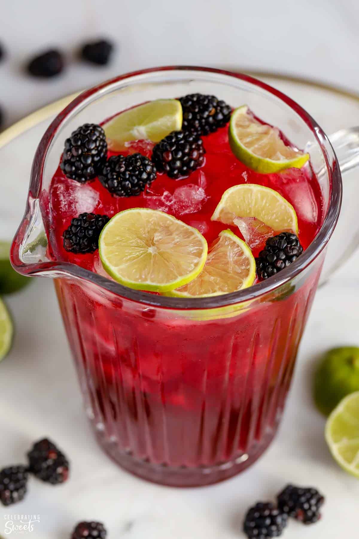Pitcher of blackberry margaritas garnished with lime slices and fresh blackberries.