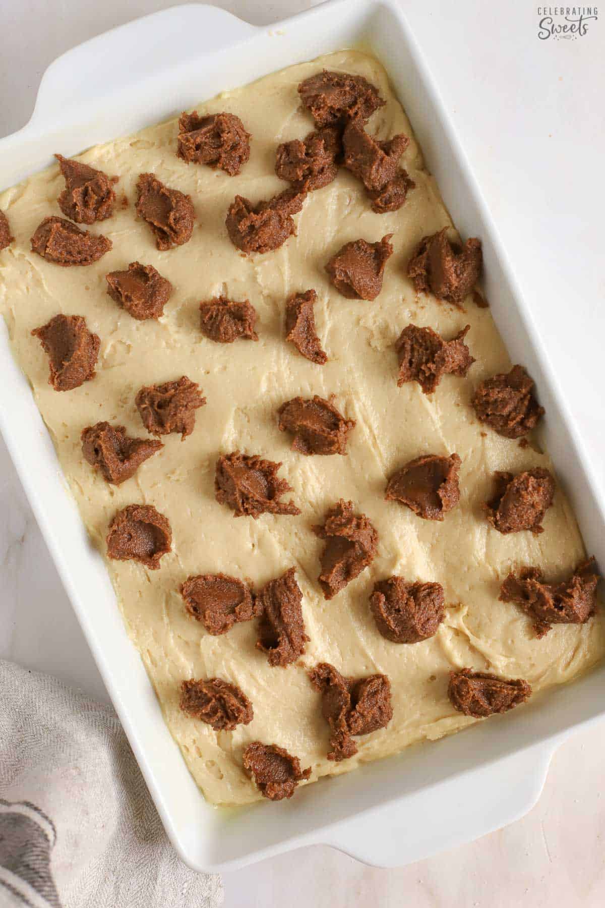 Dollops of cinnamon butter on cake batter in a white pan.