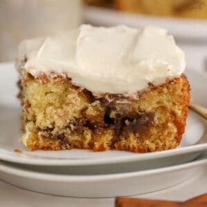 Slice of cinnamon roll cake on a white plate.