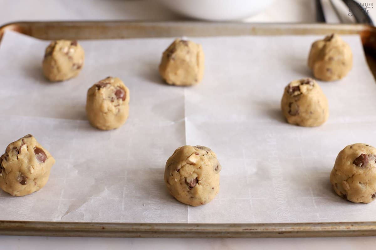 Cookie dough on a parchment lined baking sheet.