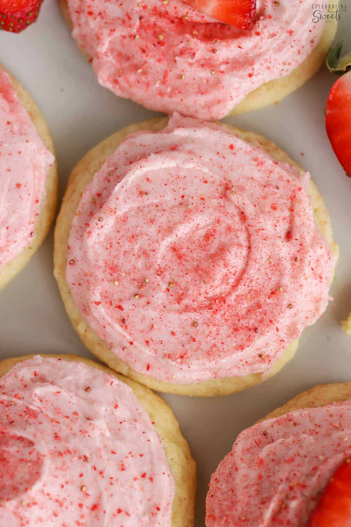 Closeup of sugar cookies topped with pink strawberry frosting.