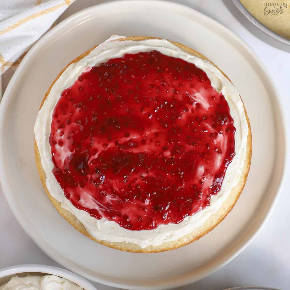 Cake topped with white frosting and raspberry jam.