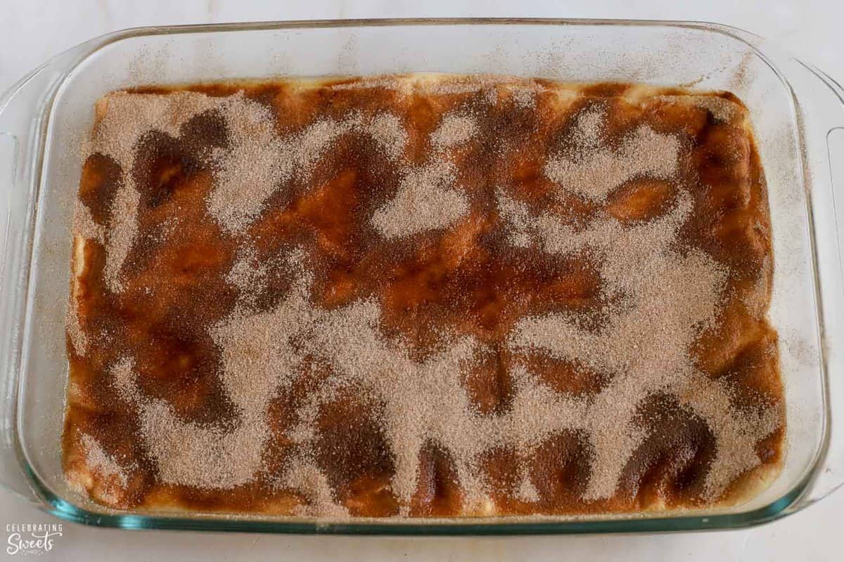 Cinnamon sugar on top of crescent dough in a glass pan.