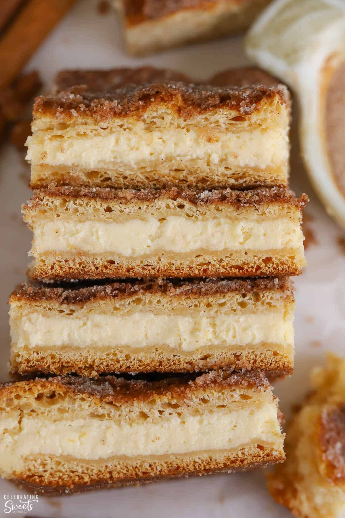 Four churro cheesecake bars next to a bowl of cinnamon sugar.