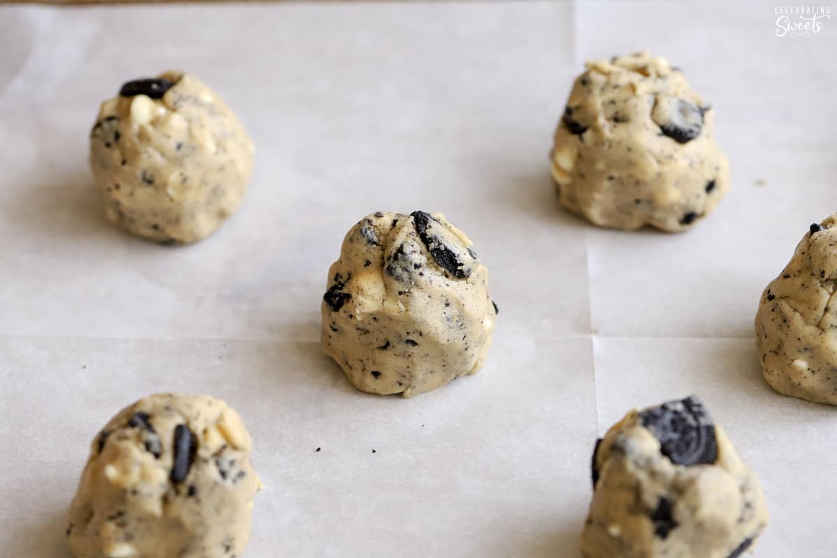 Cookie dough balls on a parchment lined baking sheet.