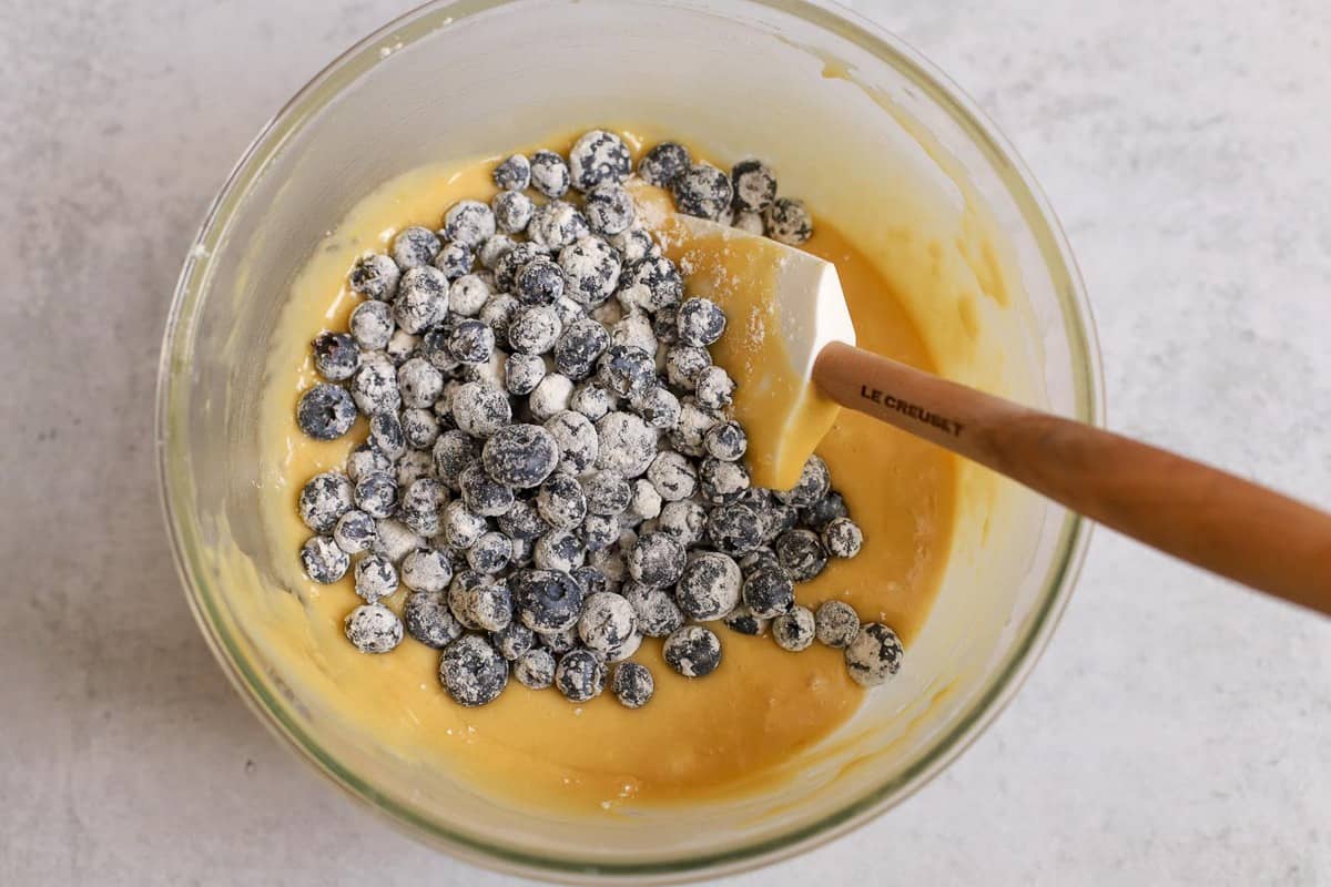 Glass bowl with lemon cake batter and fresh blueberries.