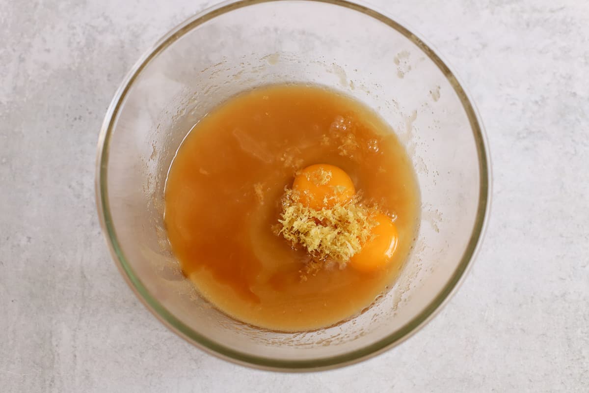 Eggs, melted butter, lemon zest in a glass bowl.