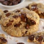 Oatmeal cookie broken in half filled with chocolate chips.