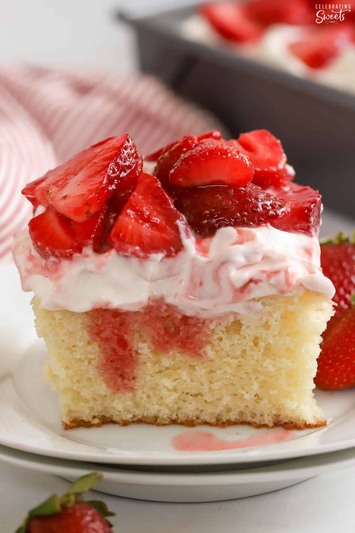 Slice of strawberry shortcake sheet cake on a white plate.