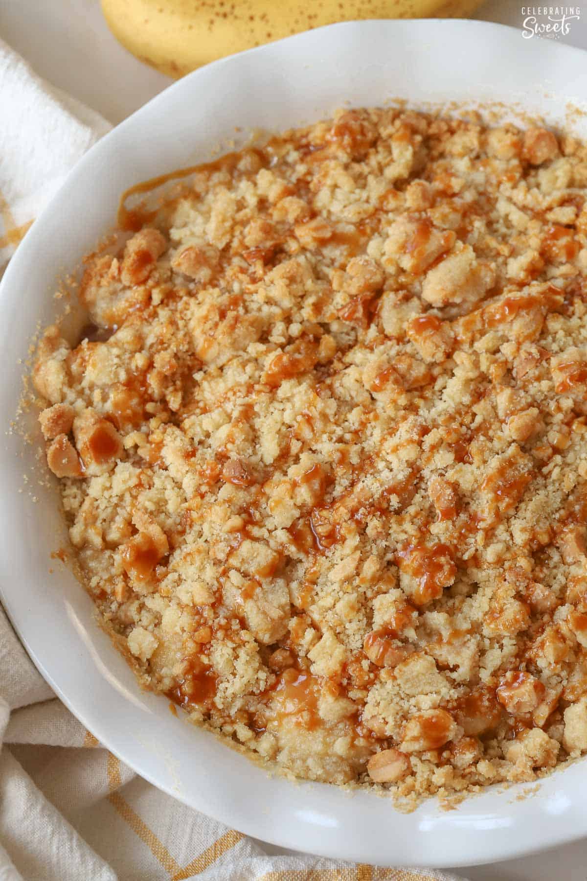 Banana crumble topped with caramel drizzle in a white baking dish.