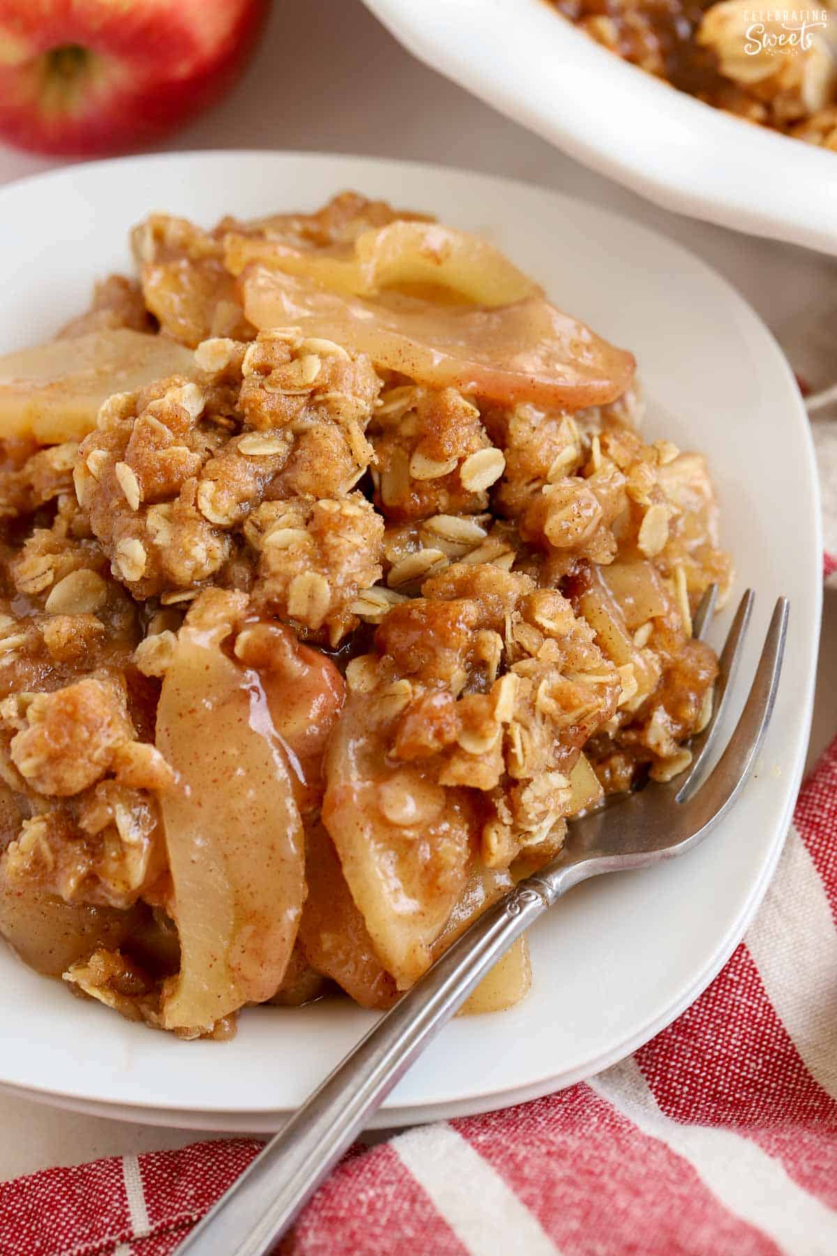 Apple crisp on a white plate with a silver fork,
