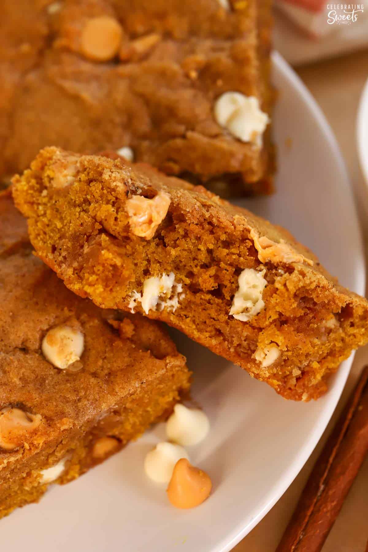 Pumpkin blondie with a bite taken out of it on a white plate.