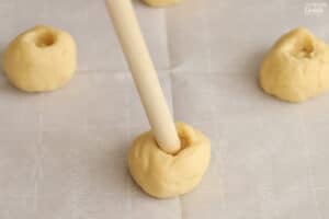 End of a wooden spoon being pushed into a ball of cookie dough.