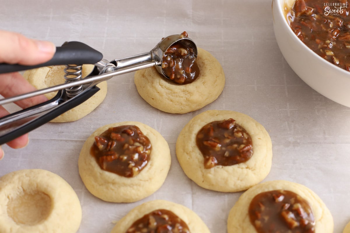 Pecan pie filling being scooped onto a sugar cookie.