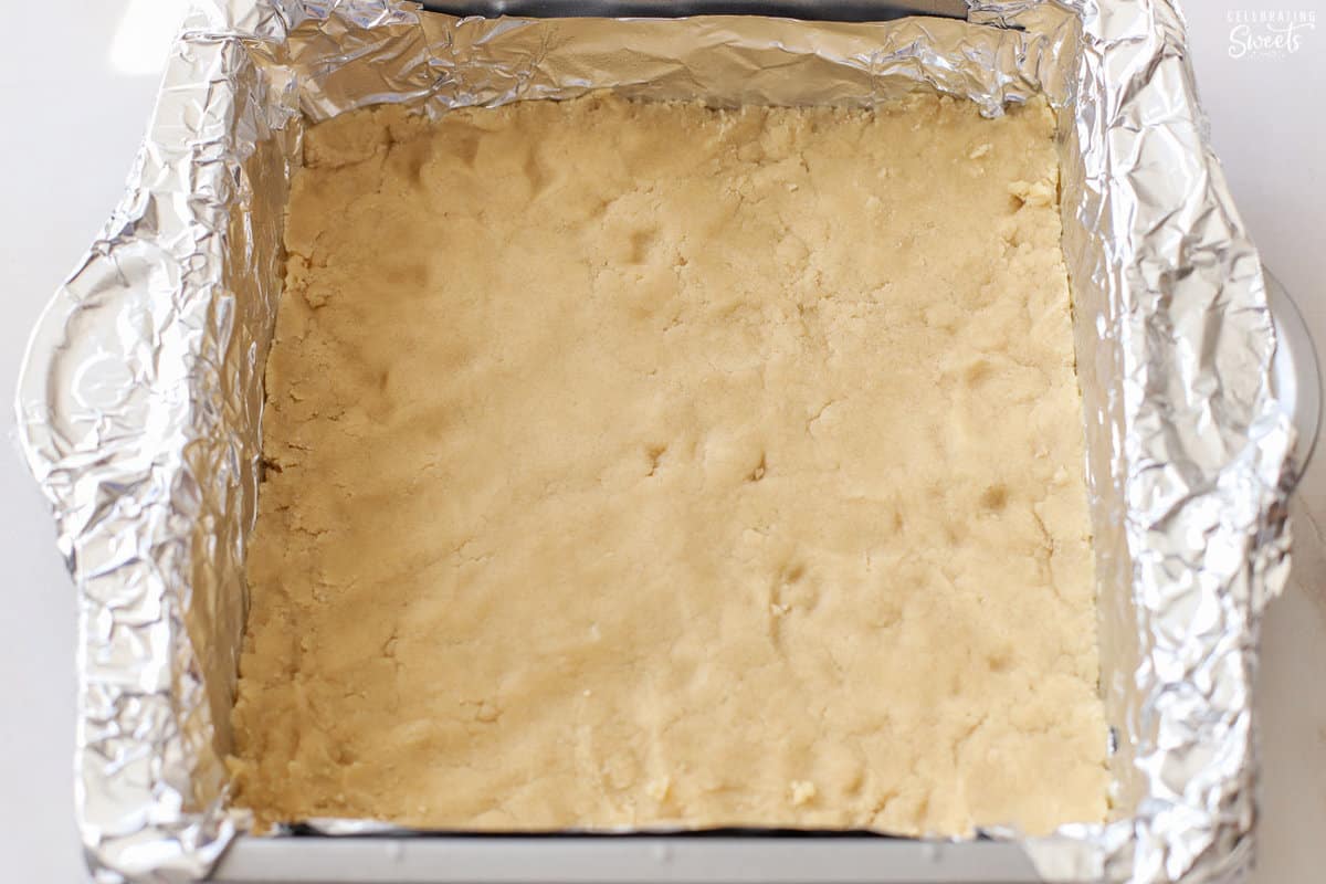 Unbaked shortbread crust in a foil-lined baking dish.