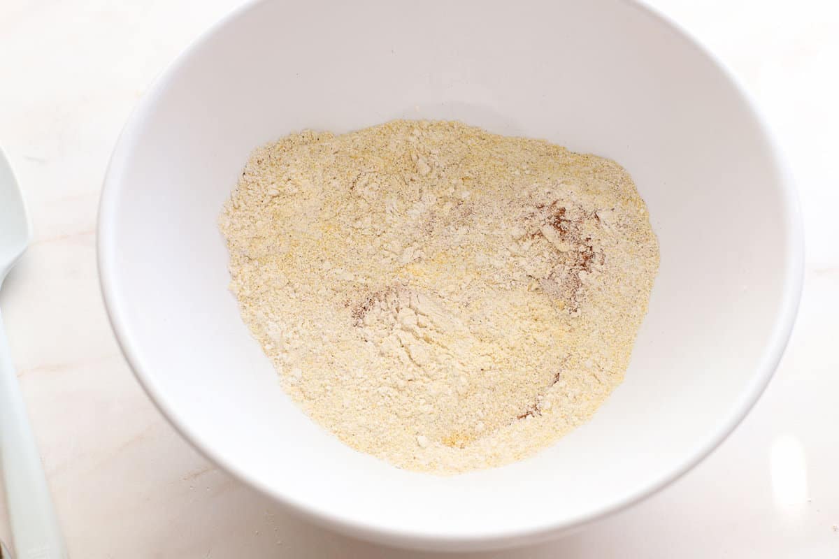 White bowl filled with flour, cornmeal, and spices.
