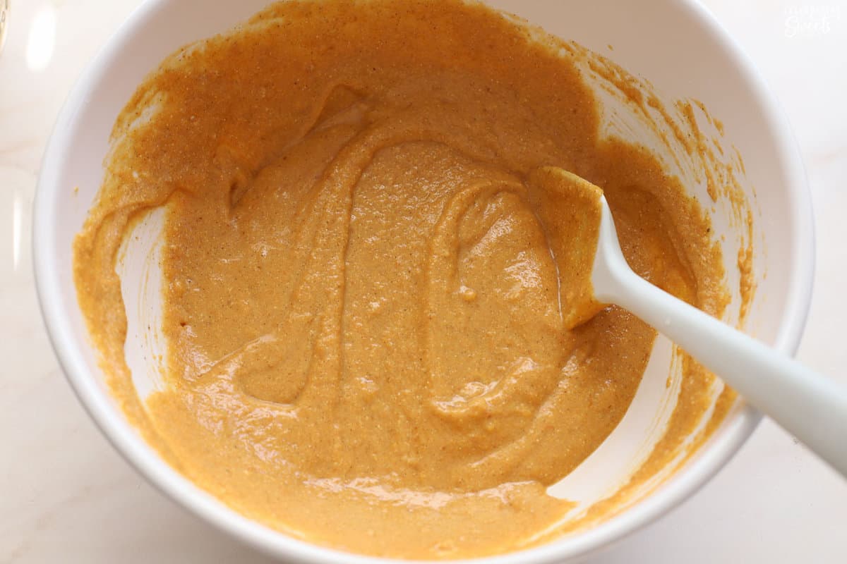 Pumpkin cornbread batter in a white bowl.